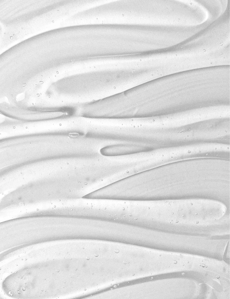 Close-up of a clear gel texture, possibly a skincare product. The fluid lines suggest the sensory experience of applying a product, highlighting the "rituel émotionnel" aspect of the article.
