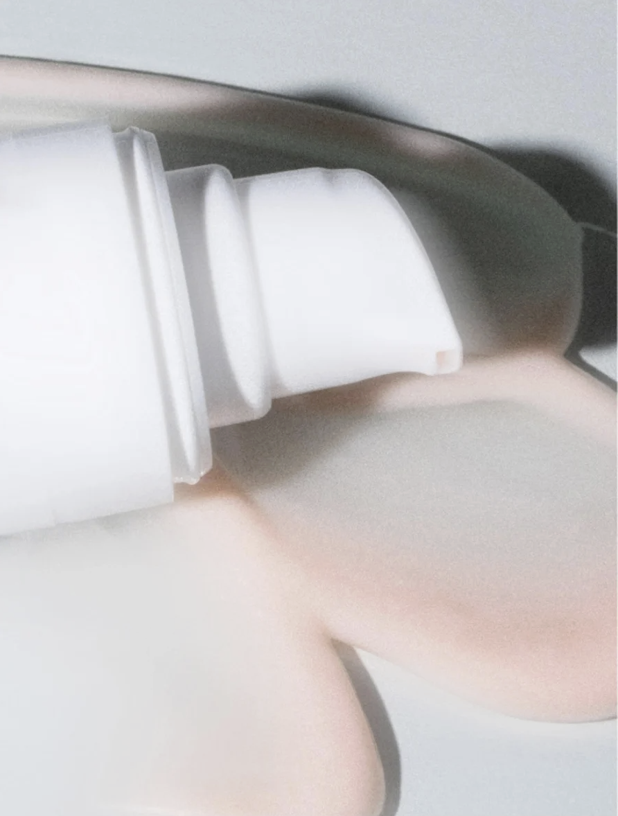Close-up of a white skincare product bottle dispensing a creamy substance, representing a step in transforming a skincare routine into an emotional ritual.
