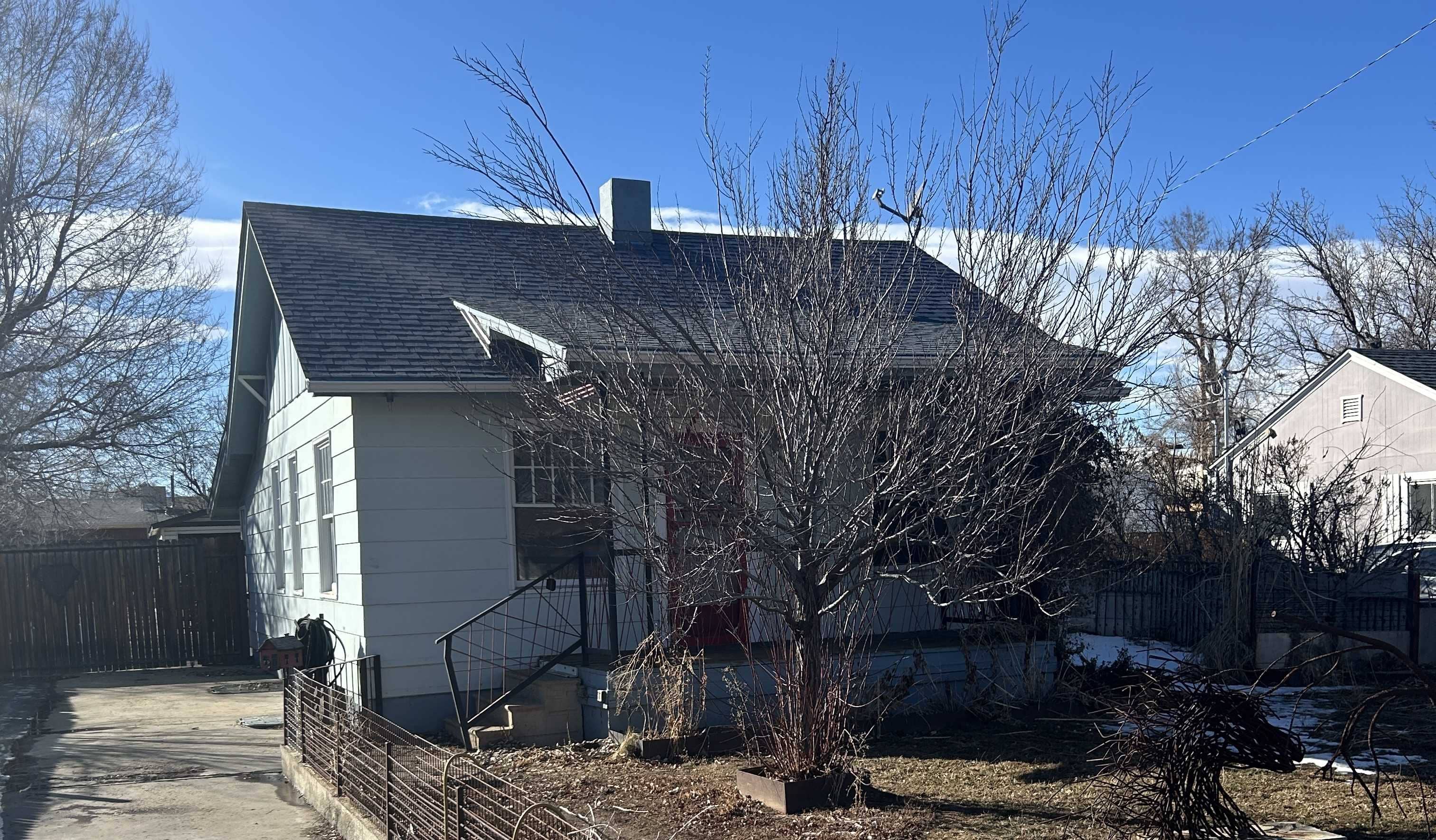 Old house with a sloped roof, bare trees, and a concrete path, illustrating renovation potential for selling homes quickly and profitably.