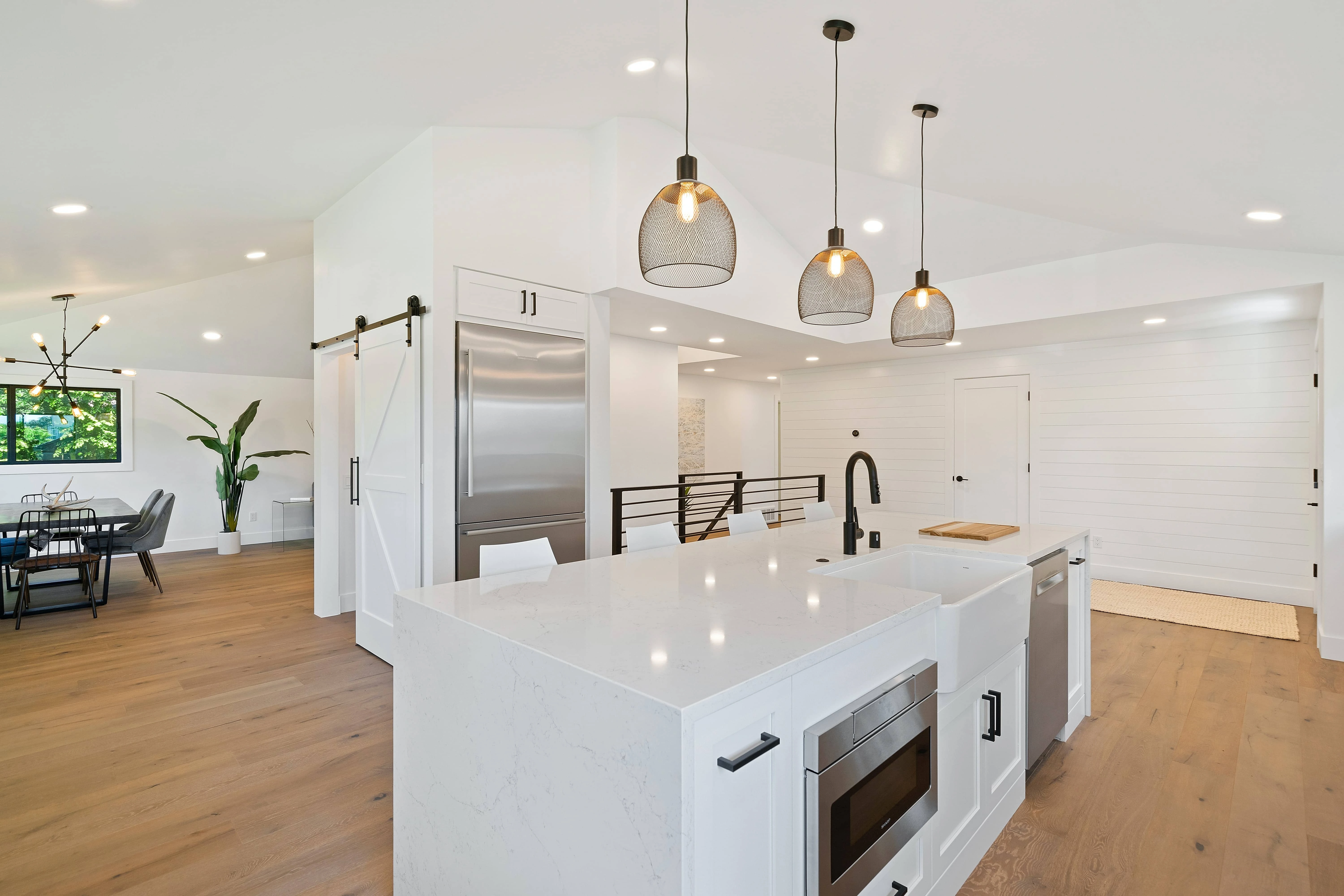 Modern, bright kitchen with white countertops, pendant lights, open-plan dining area, and sleek appliances; ideal for boosting old home sales.