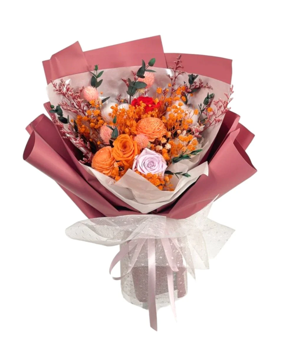 A bouquet of preserved orange and light pink flowers in a pink wrap, elegantly arranged in a vase, perfect for home decoration.