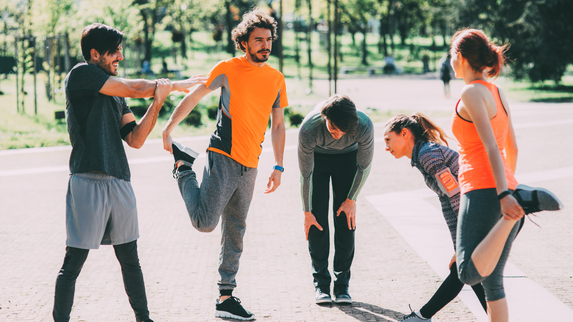 Group of people stretching outdoors during a workout session.