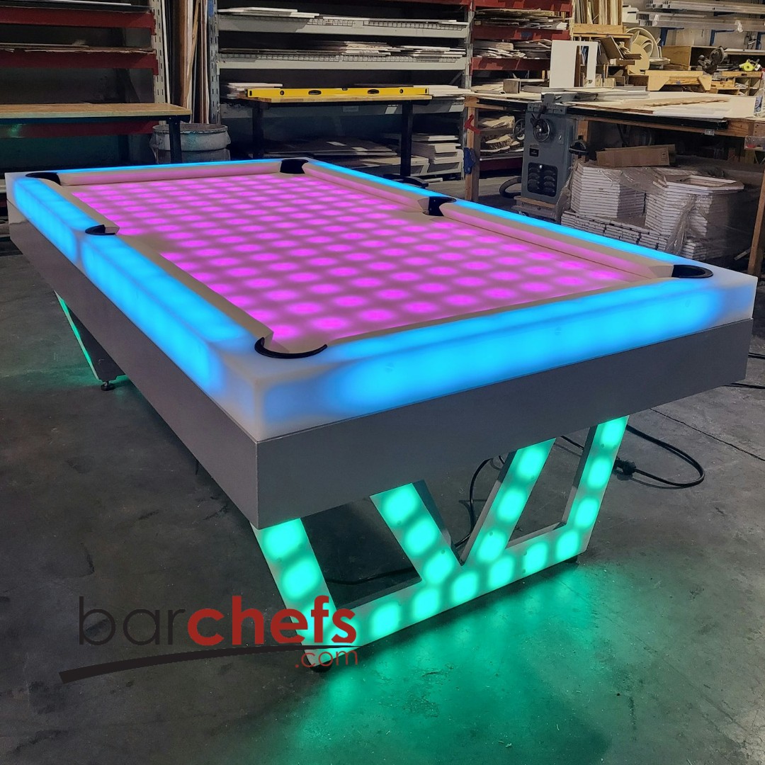 A glowing LED billiards table with vibrant pink and blue lights.